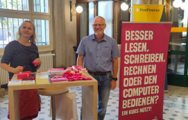 Un homme et une femme devant un présentoir à prospectus à la Poste. Ils sensibilisent le public aux compétences numériques.